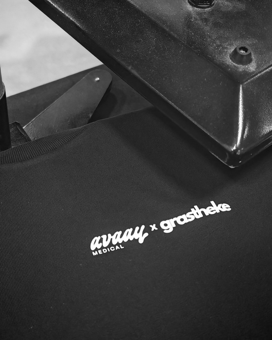 Collab-Motiv avaay medical und grastheke auf einem schwarzen T-Shirt unter der Transferpresse